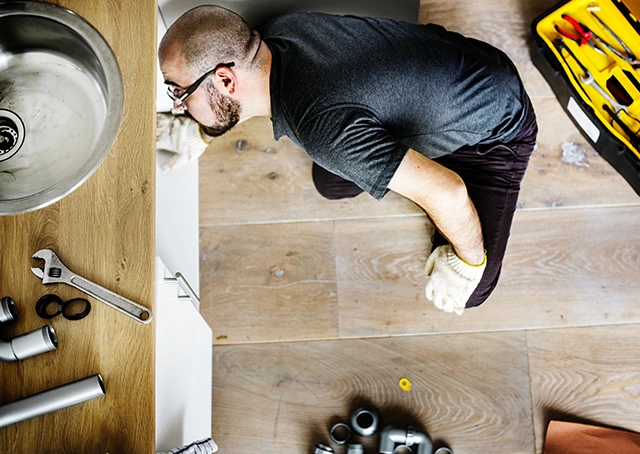 Installation plomberie sous évier dans une maison neuve avec outils professionnels